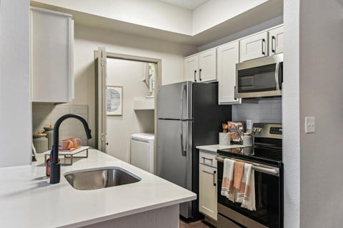 A kitchen with a black refrigerator and white countertops.at Onyx183, Austin, TX  