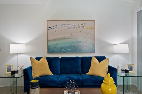 a living room with a blue couch and a painting on the wall