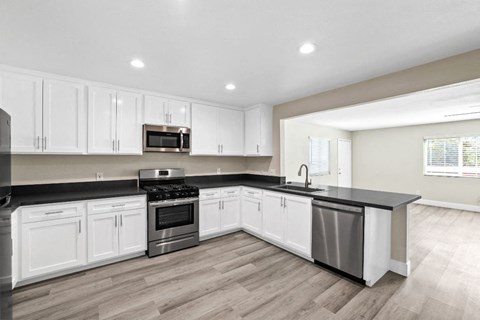 a kitchen with white cabinets and a black counter top
