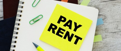 A neon post-it on a notebook with the "pay rent" message written on it to illustrate a late rent notice.
