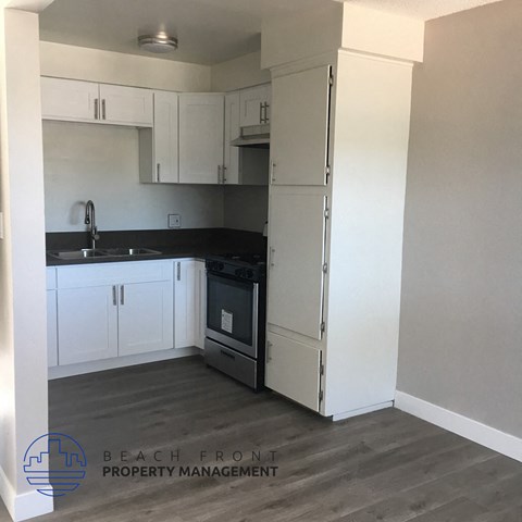 a kitchen with white cabinets and a sink and a refrigerator