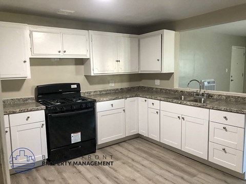 A kitchen with white cabinets and a black stove top oven.