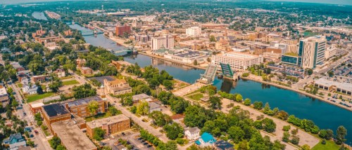 The U.S. hottest rental markets in peak season 2024 feature Suburban Chicago at a tie with Miami for first place. Aerial view of downtown Joliet, IL (in suburban Chicago) showcasing its riverfront, historic architecture, and urban landscape.