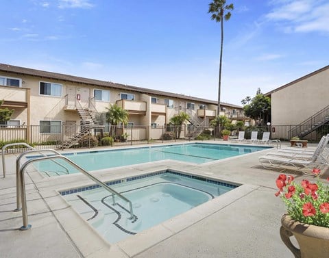 A pool surrounded by chairs and a building in the background.