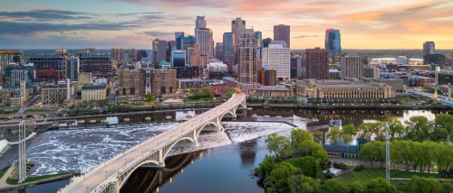 View of Minneapolis, MN city skyline over the river at dusk.