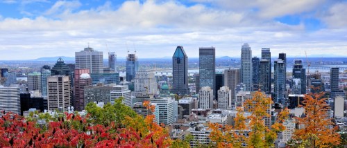 A vibrant skyline view of downtown Montreal, Canada, framed by autumn foliage.