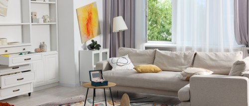 Neutral-toned living room with a beige sofa, modern art, open drawers, a jewelry box on the table, showing signs of burglary and highlighting the importance of theft protection.