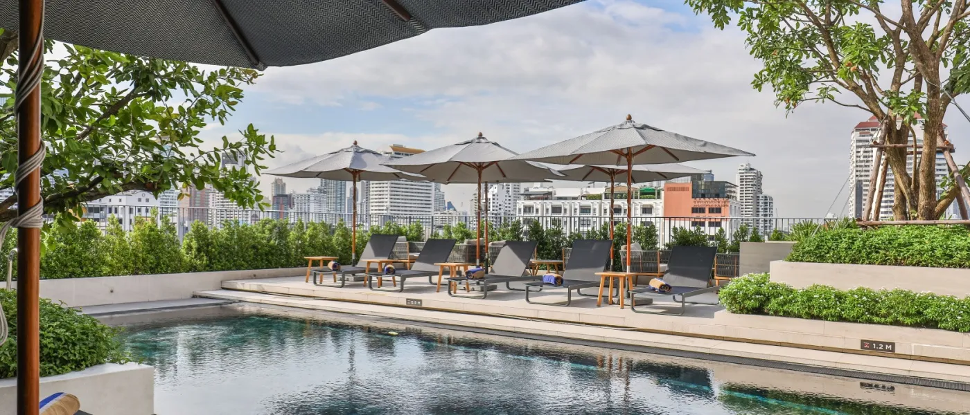 View of a luxury rooftop pool with sun loungers and umbrellas to illustrate apartment amenities.