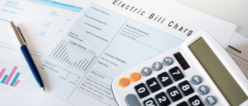 Bills for an apartment with utilities included, including gas and electric charges, alongside a calculator and pen on a white desk.